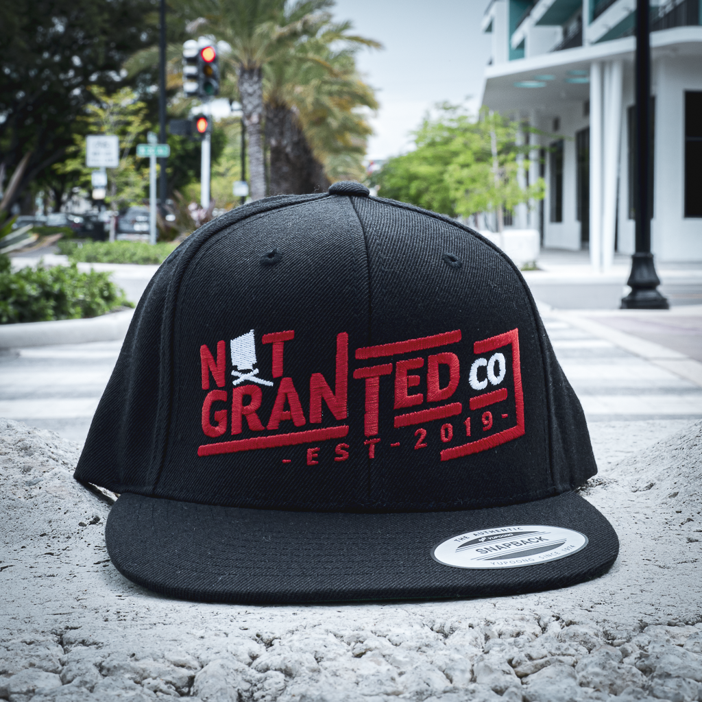 Black cap with red and white text on a street background